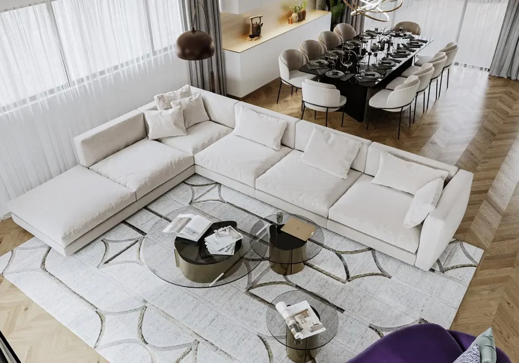 ספה גדולה בצבע שמנת ממוקמת בסלון, לידה שולחנות קפה זכוכית, מול שולחן אוכל גדול עם כיסאות.