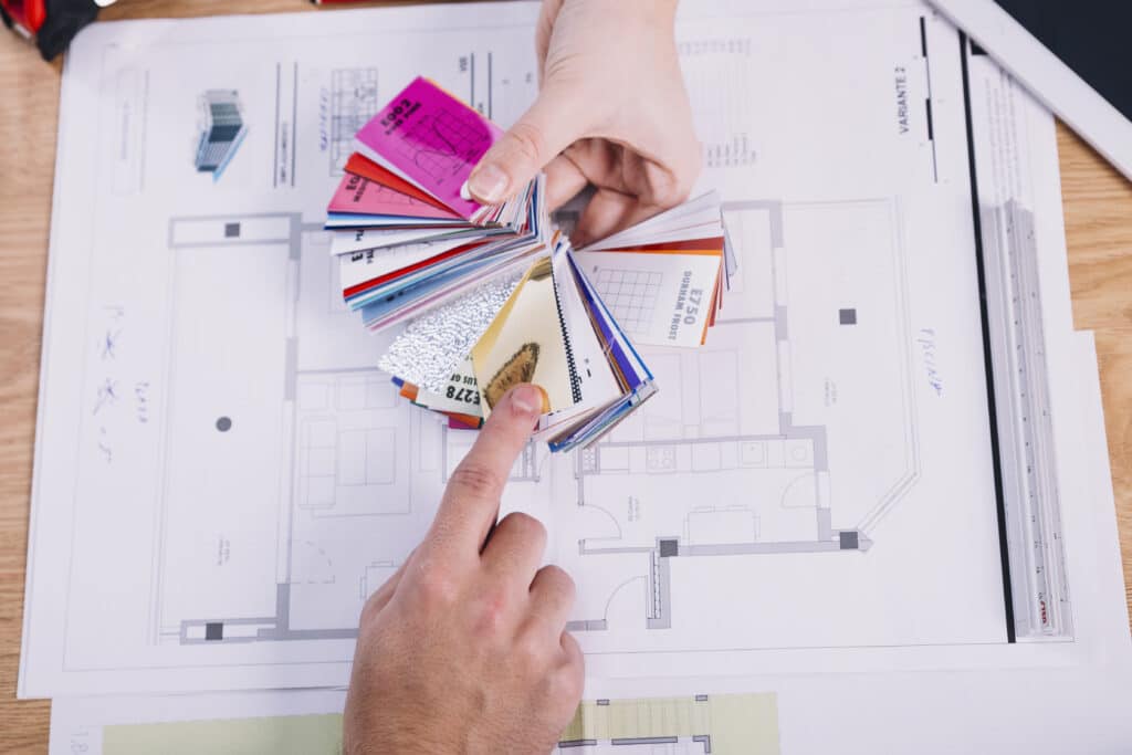 שרטוט של מבנה ומעליו פלטת צבעים שמעצבת פנים אחוזת והלקוח מצביע על הצבע