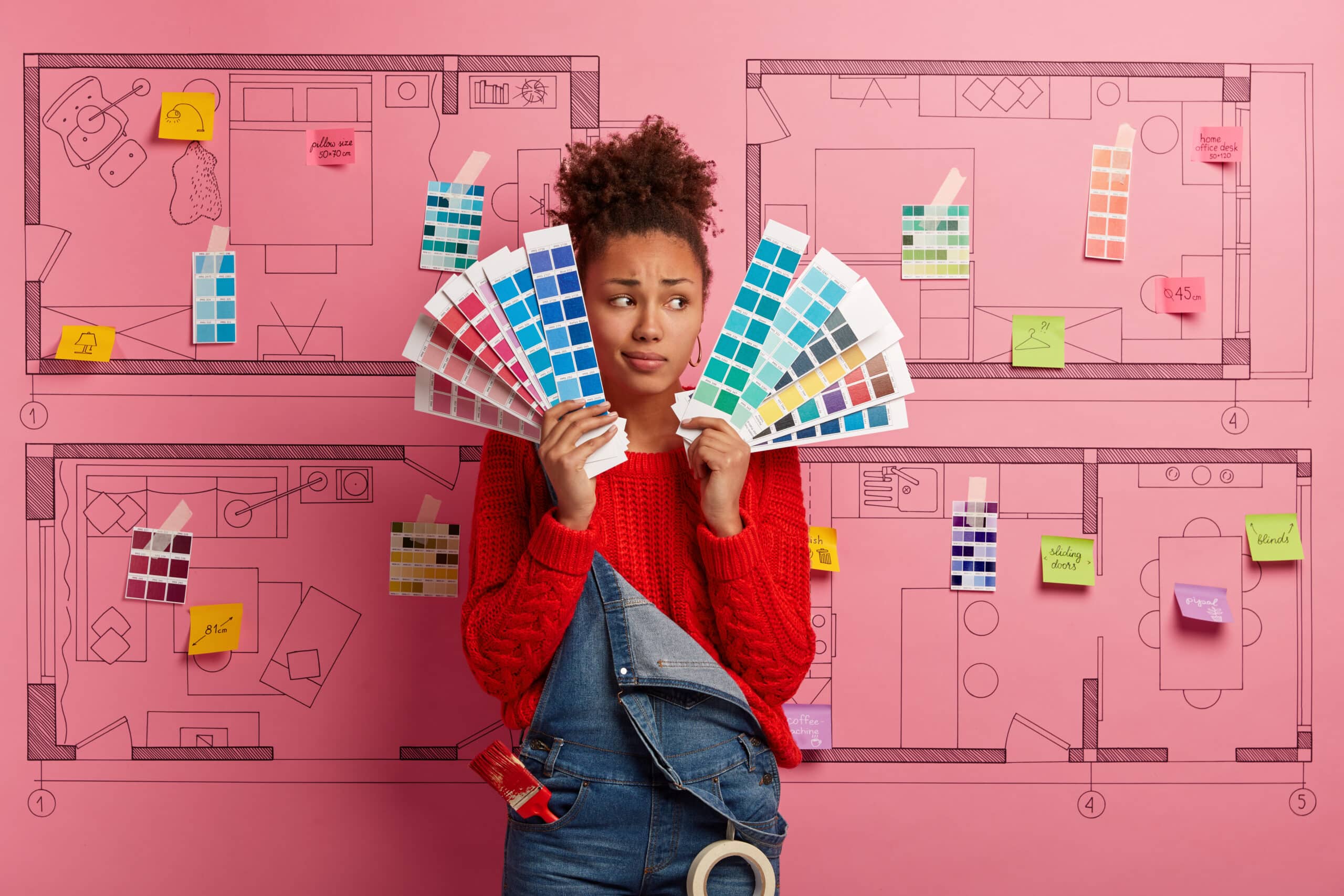 אישה מחזיקה פלטות צבעים ומאחוריה רקע של שרטוט של בית